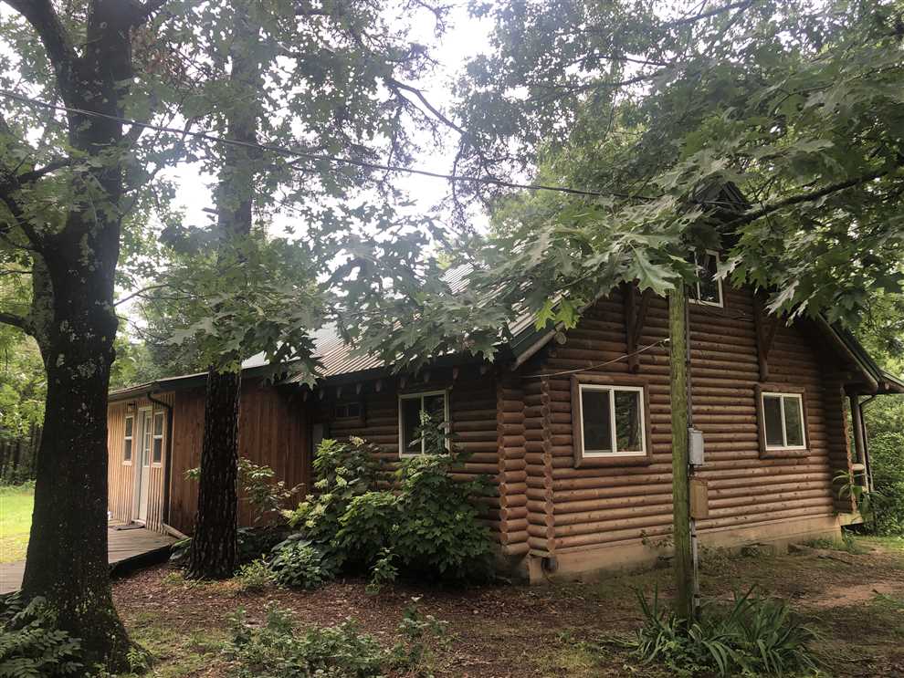 Secluded 2BR / 1BA Log Cabin w/ big loft and big front porch sitting at the end of county dirt road on 8.66 + or -wooded level acres w/utilities . Real estate listing